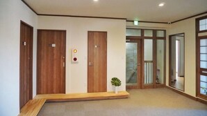Ein Korridor mit Holztüren, einer kleinen Pflanze und einer Treppe, die zu einem Balkon führt.
