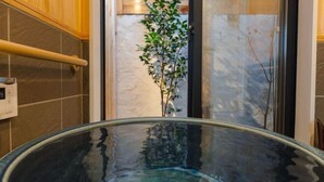 Een houten terras met een glazen hottub en een plant op de achtergrond.
