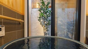 Een hottub met glazen wanden en een plant op de achtergrond.