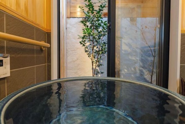 A glass-enclosed hot tub with a plant in the background. - Kyoto Amazing The Wizarad of Oz (Kyoto)
