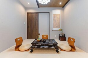A dining area with a wooden table, two chairs, and a vase with flowers. - Kyoto Amazing The Wizarad of Oz (Kyoto)