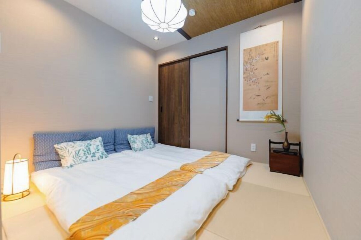 A bedroom with a bed, a nightstand, a wall-mounted lamp, and a ceiling light fixture.