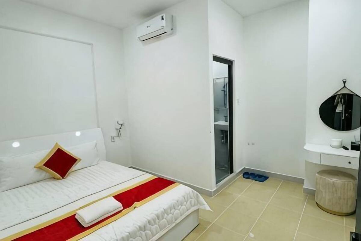 Une chambre d’hôtel avec un lit, un petit bureau, un miroir et une porte de salle de bain.