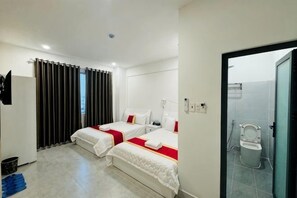Ein Hotelzimmer mit zwei Betten, einer Dusche und Blick auf die Stadt.