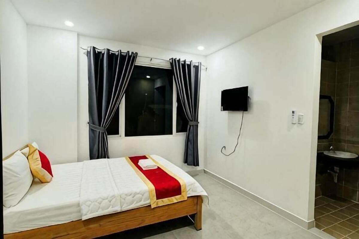 Une chambre à coucher avec un lit, des rideaux, une télévision et une salle de bain.
