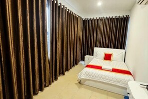 A bedroom with a bed, curtains, a bedside table, and a nightstand. - Phu Gia 2307 Huynh Tan Phat (Ho Chi Minh City)