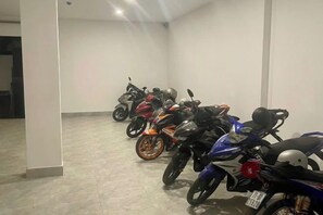 Een rij motorfietsen geparkeerd in een ruimte, met een effen muur en een deur op de achtergrond.