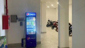 A hallway with a Pepsi vending machine, a fire extinguisher, and a motorcycle parked in the background. - Phu Gia 2307 Huynh Tan Phat (Ho Chi Minh City)