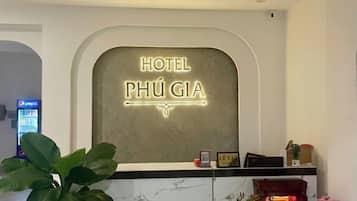 Una recepción con un letrero de neón que dice 'HOTEL PHÚ GIÁ' y una planta a la izquierda.