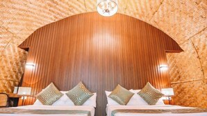 Una habitación con dos camas, paneles de madera en las paredes y techo tejido.