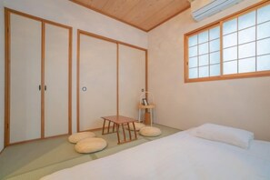 A traditional Japanese-style room with tatami flooring, a low bed, and sliding doors. - Travel Time・Hanazonochō｜Direct train access to Shinsekai, Namba, and Dotonbori in 5 minutes (Osaka)