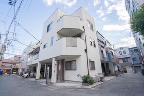 A multi-story residential building with a flat roof, balconies, and a visible entrance. - Travel Time・Hanazonochō｜Direct train access to Shinsekai, Namba, and Dotonbori in 5 minutes (Osaka)