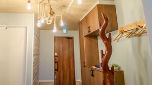 A hallway with wooden doors, a wooden cabinet, a wooden sculpture, and a ceiling light fixture. - Le Grand Bleu Resort Nagasawa (Yokosuka)