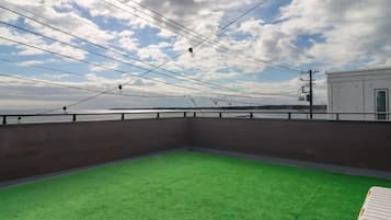 An outdoor area with a green surface, a wooden fence, and a view of the sky and distant structures.