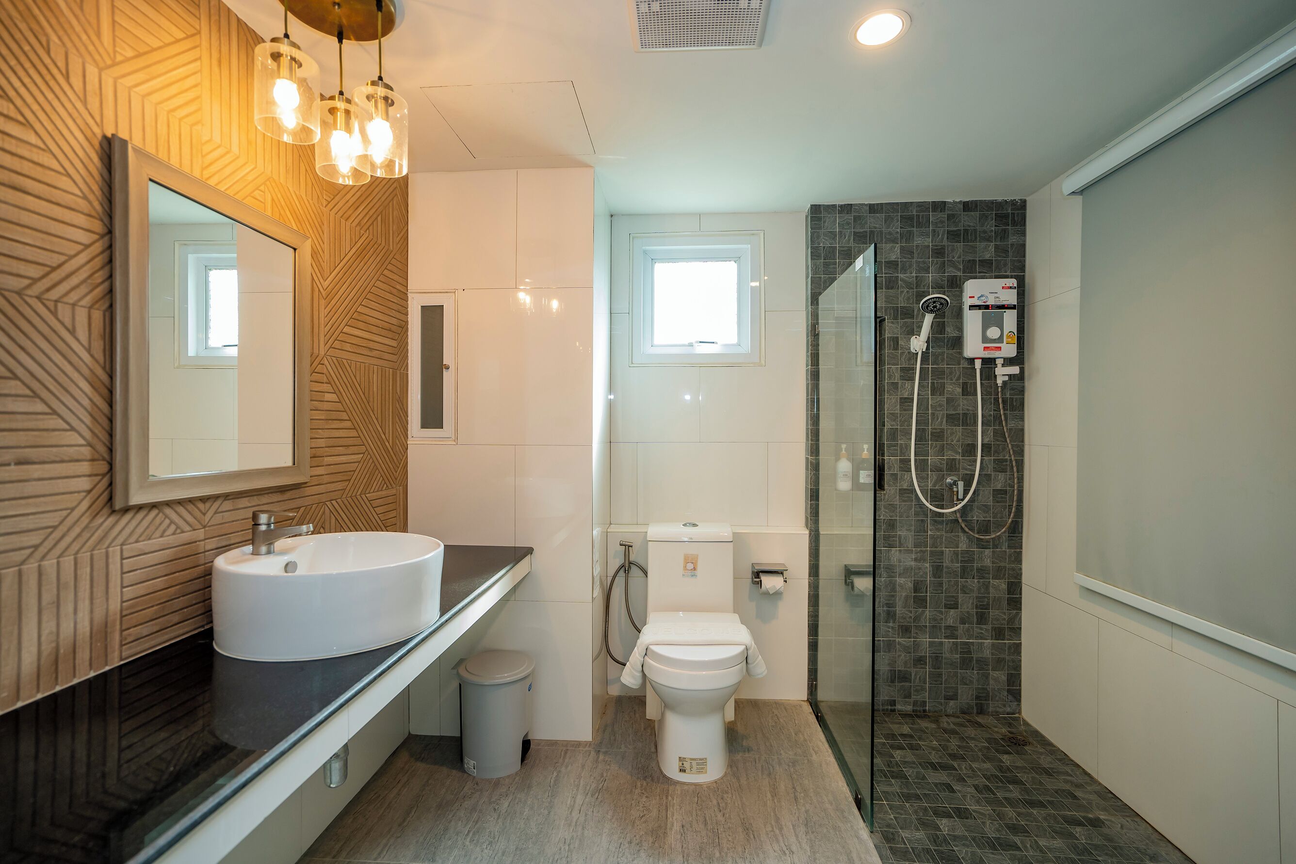 Un bagno moderno con un grande specchio, un lavabo, un water e una zona doccia.