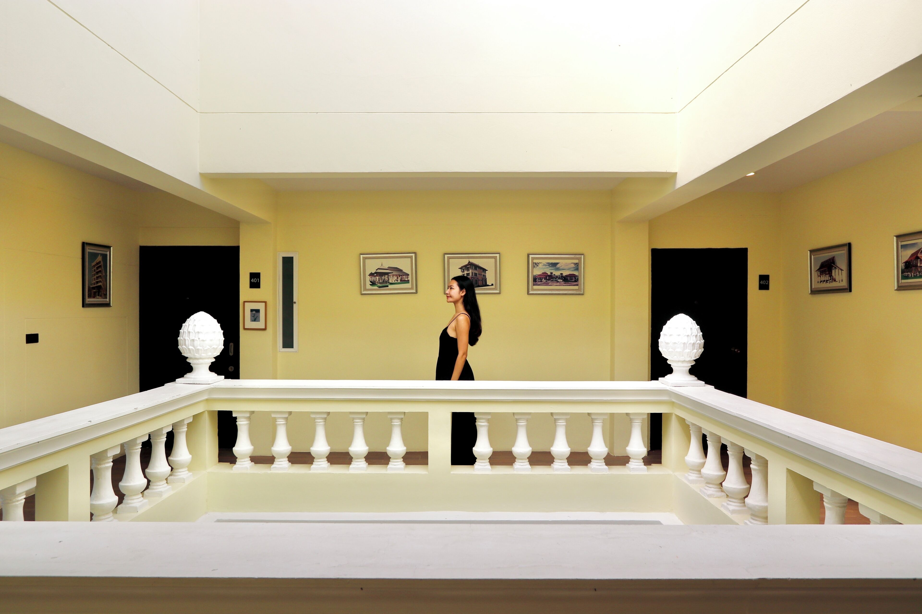 A hotel lobby with a white balustrade, yellow walls, and framed pictures on the walls.