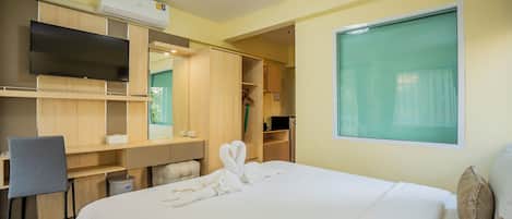 A hotel room with a bed, a desk, a chair, a TV, a wardrobe, and a window.