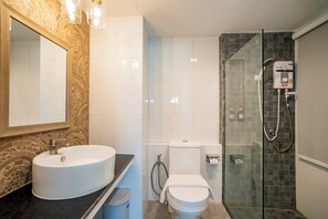 A bathroom with a double sink, a toilet, a glass shower enclosure, and a mirror with a patterned frame.