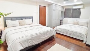 Une chambre d’hôtel avec deux lits, une armoire, une fenêtre et un luminaire au plafond.