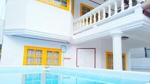 Un bâtiment blanc avec des fenêtres à cadre jaune et un balcon doté de balustrades blanches.