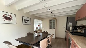 Una cucina moderna con zona pranzo, che include un tavolo e sedie in legno, un frigorifero e pensili.