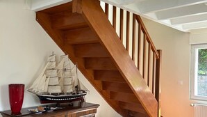 Una scala in legno in una stanza con un armadio di legno e una nave in miniatura.
