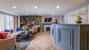 Un soggiorno moderno con camino, una libreria e un cartello che indica "Maple Valley Guest House".