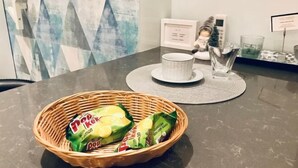 A table with a wicker basket containing Pop Kettle packets, a white cup, and a glass on a marble surface. - INNA LUXE (Belgrade)
