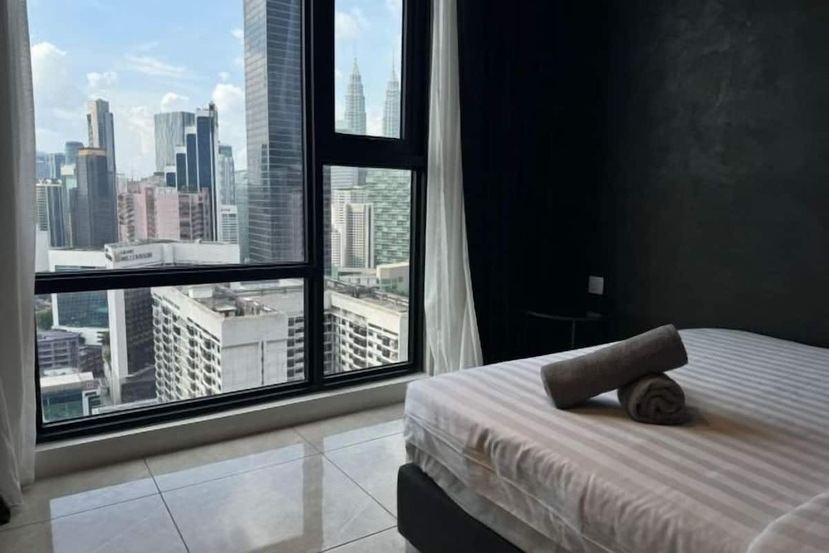 A hotel room with a large window offering a city view, a neatly made bed, and a modern design.