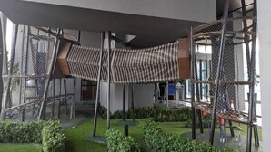 Un edificio moderno con un espacio al aire libre cubierto, que incluye una estructura para escalar y un pequeño jardín.