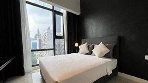 Una habitación de hotel moderna con una cama grande, vistas a la ciudad y una pared de acento negra.