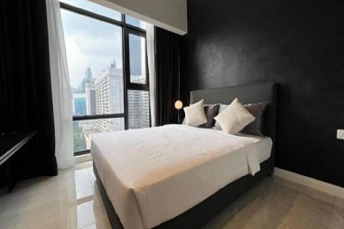 A modern hotel room with a large bed, a view of the city, and a black accent wall.