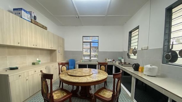 A compact kitchen with a round dining table, wooden chairs, and a window with a view. - Ayana Homestay (Labuan)