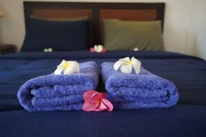 Ein Bett mit blauer Bettwäsche, zwei Handtücher mit Blumenmuster und ein Kopfkissen.