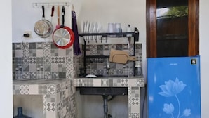 A kitchen with a tiled backsplash, a sink, a water dispenser, and a blue refrigerator.