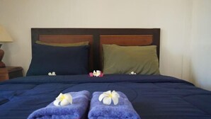 A bed with a dark blue bedspread, two pillows, and two towels with flowers.