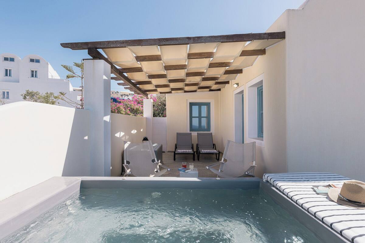 Ett poolområde på taket med en pergola, solstolar och ett litet bord med drycker.