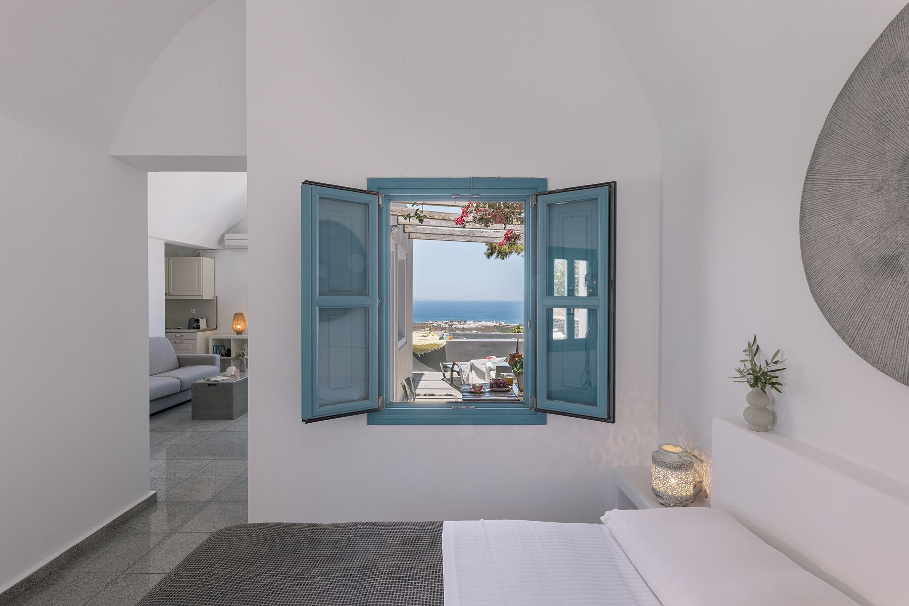 Quarto com vista para o mar, uma pequena varanda e área de jantar com mesa e cadeiras.