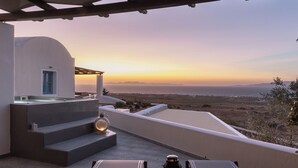 A terrace with a view of the sea at sunset, outdoor seating, and a small water feature. - GTK Santorini Oia Sunset Villas (Santorini)