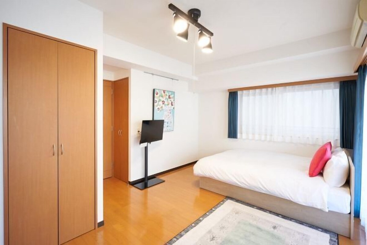 Ein Schlafzimmer mit Bett, Kleiderschrank, Flachbildfernseher und Deckenleuchte.