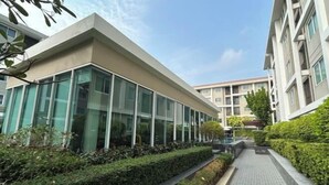 A modern building with large glass windows and a paved walkway. - Peaceful Stay @MT Khlong Luang (Khlong Luang)