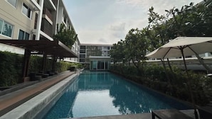 A swimming pool with a modern building in the background. - Peaceful Stay @MT Khlong Luang (Khlong Luang)