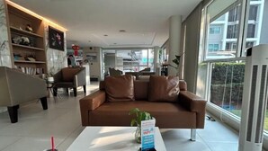 A modern living room with a brown leather sofa, a white coffee table, and a large window providing a view of the outside. - Peaceful Stay @MT Khlong Luang (Khlong Luang)