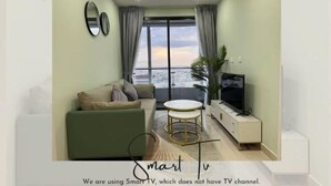 Un salon avec un canapé, un téléviseur, une petite table et une vue sur le balcon.