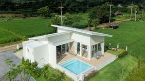 A modern house with a swimming pool, surrounded by lush greenery and fields. - Vann House Chiang Rai- Near Mae Fah Luang University (Chiang Rai)