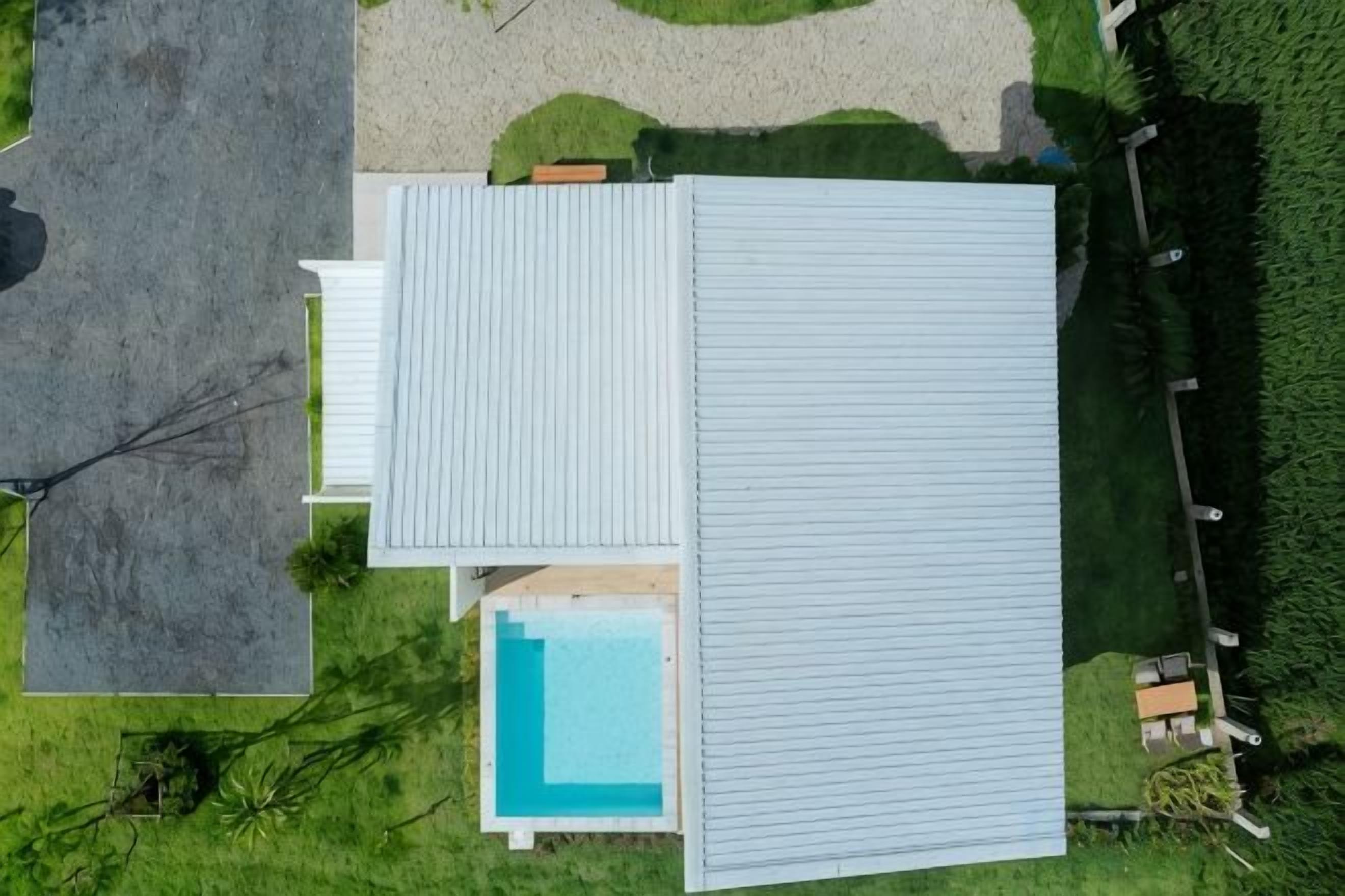 Una propiedad residencial con piscina, un porche cubierto y un césped bien cuidado.