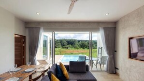 A modern room with a dining table, sofa, and a view of a swimming pool. - Vann House Chiang Rai- Near Mae Fah Luang University (Chiang Rai)