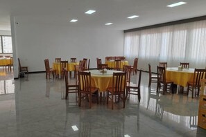 A conference room with round tables and chairs, large windows with curtains, and a tiled floor. - Ming Hua International Hotel (Boten)