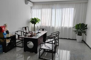 A dining area with a table and chairs, a potted plant, and a window with curtains. - Ming Hua International Hotel (Boten)