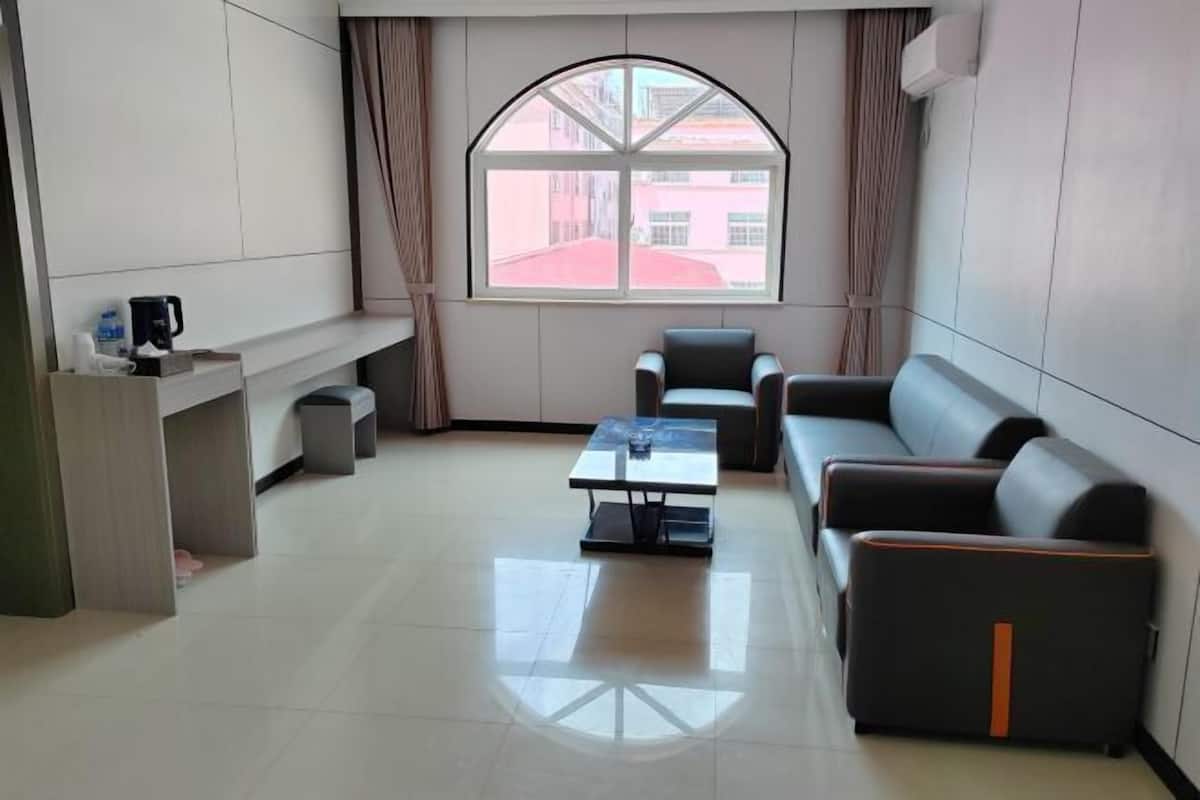 A modern living room with a sofa, a coffee table, and a window with curtains.